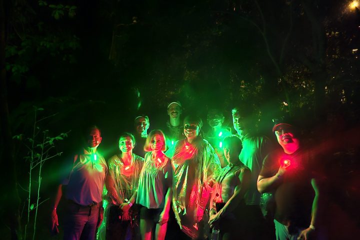 Group of people at night, illuminated by colorful lights.