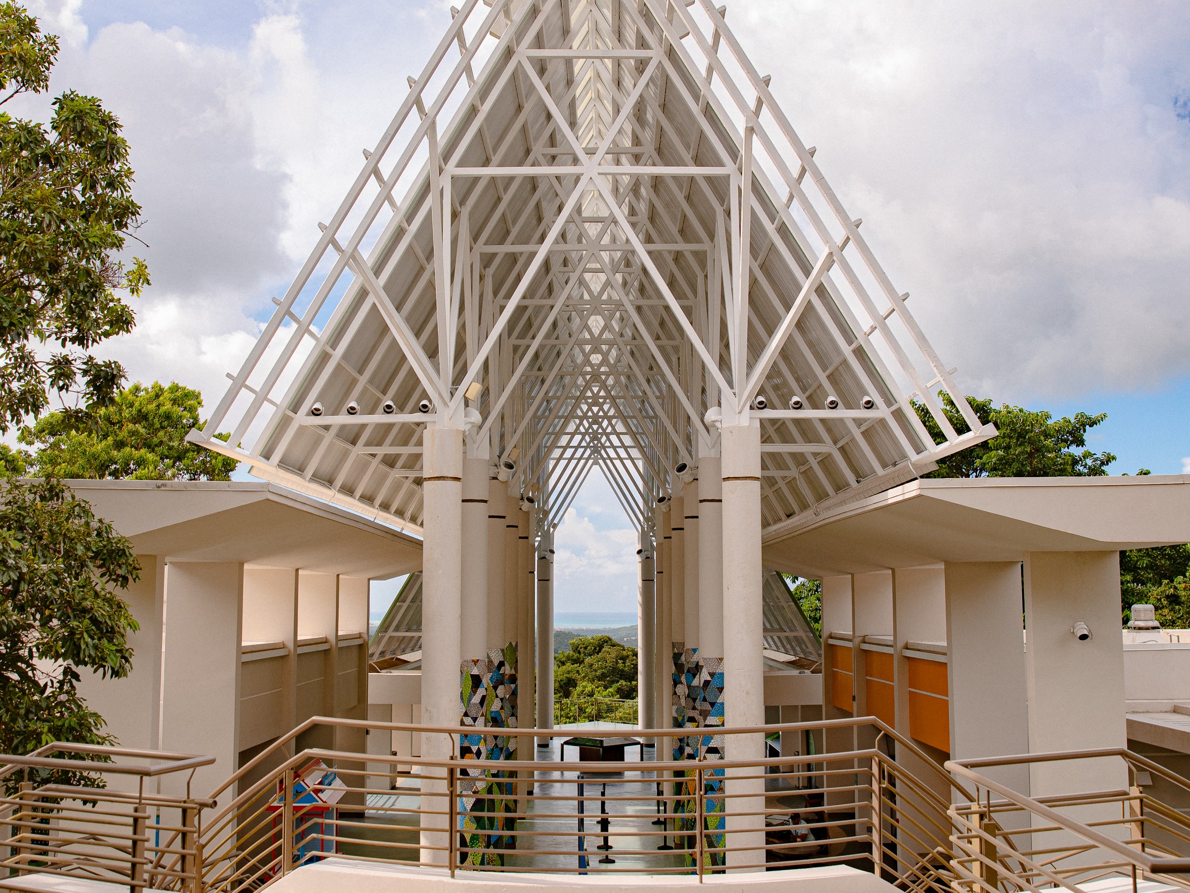 Modern open-air pavilion with white triangular roof and ocean view.