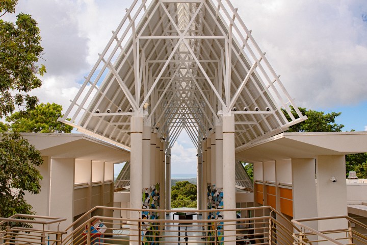 Modern open-air pavilion with white triangular roof and ocean view.