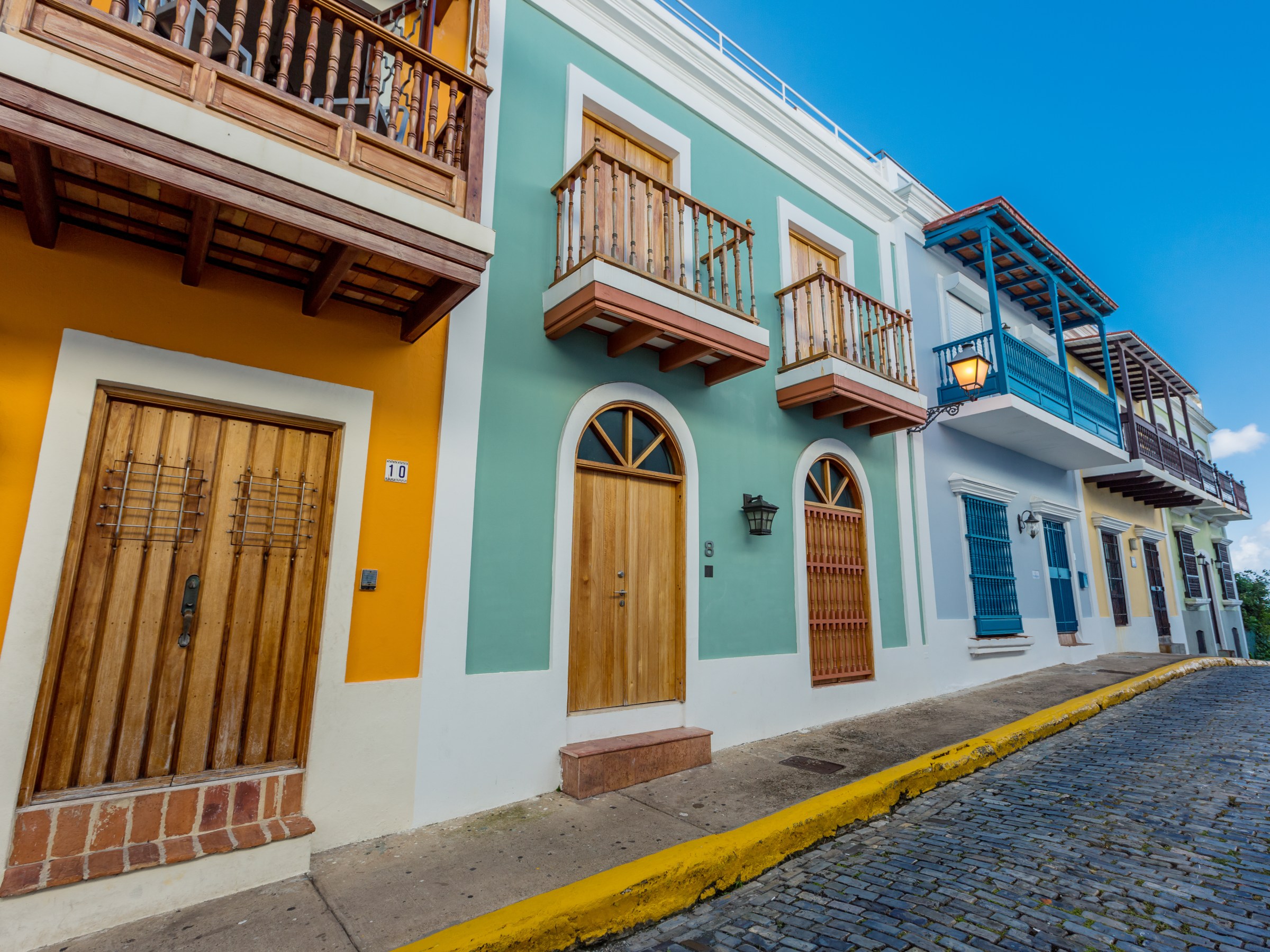 Colorful buildings with wooden doors and balconies on a cobblestone street.