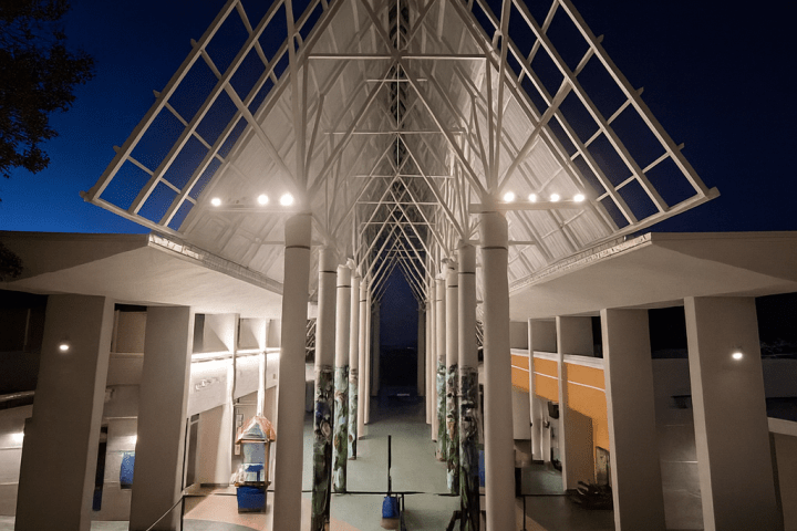 Modern architectural structure with tall columns and a peaked roof at night.