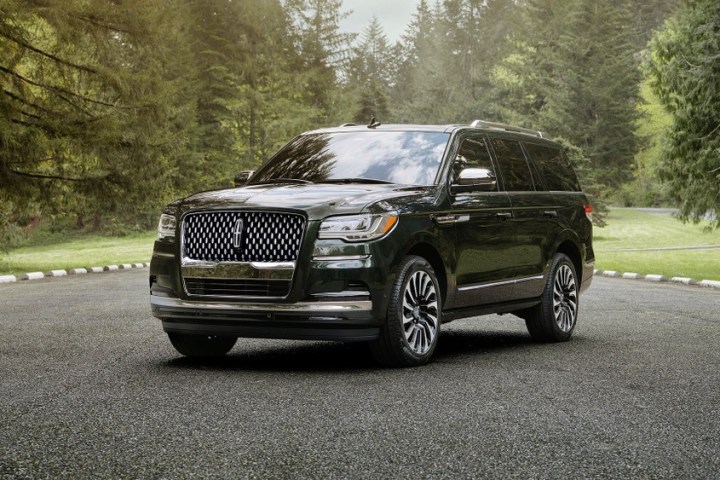 Black SUV parked on a paved road surrounded by trees and greenery.
